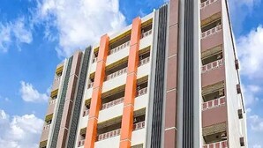 A multi-story hotel with a prominent orange facade, multiple balconies, and a clear sky in the background. - The Ring Residence (Hat Yai)