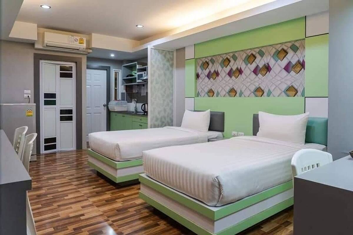 A hotel room with two beds, a desk, and a kitchenette.