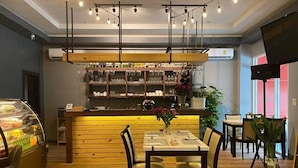 A restaurant with a wooden counter, a glass display case, and a table with chairs. - The Ring Residence (Hat Yai)