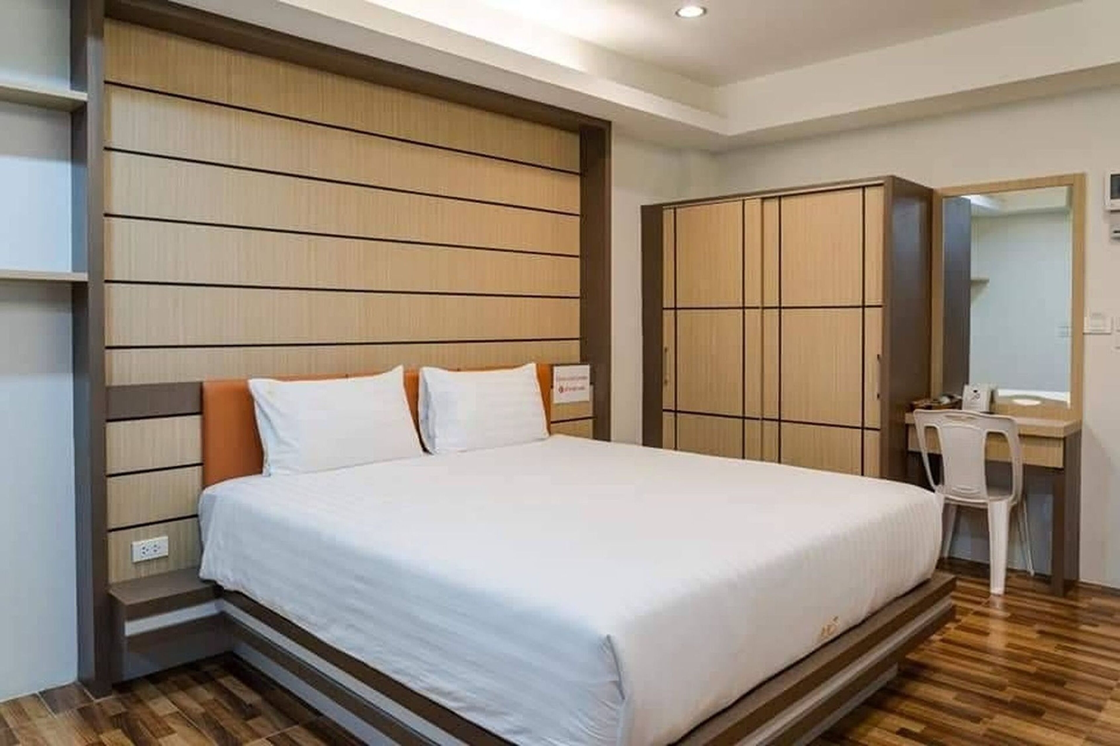 A bedroom with a bed, a wardrobe, a desk, and a mirror.