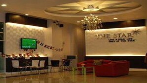 A hotel reception area with a modern design, a chandelier, a reception desk, and a red sofa.