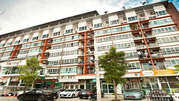 A multi-story hotel with balconies, a parking area, and several storefronts.