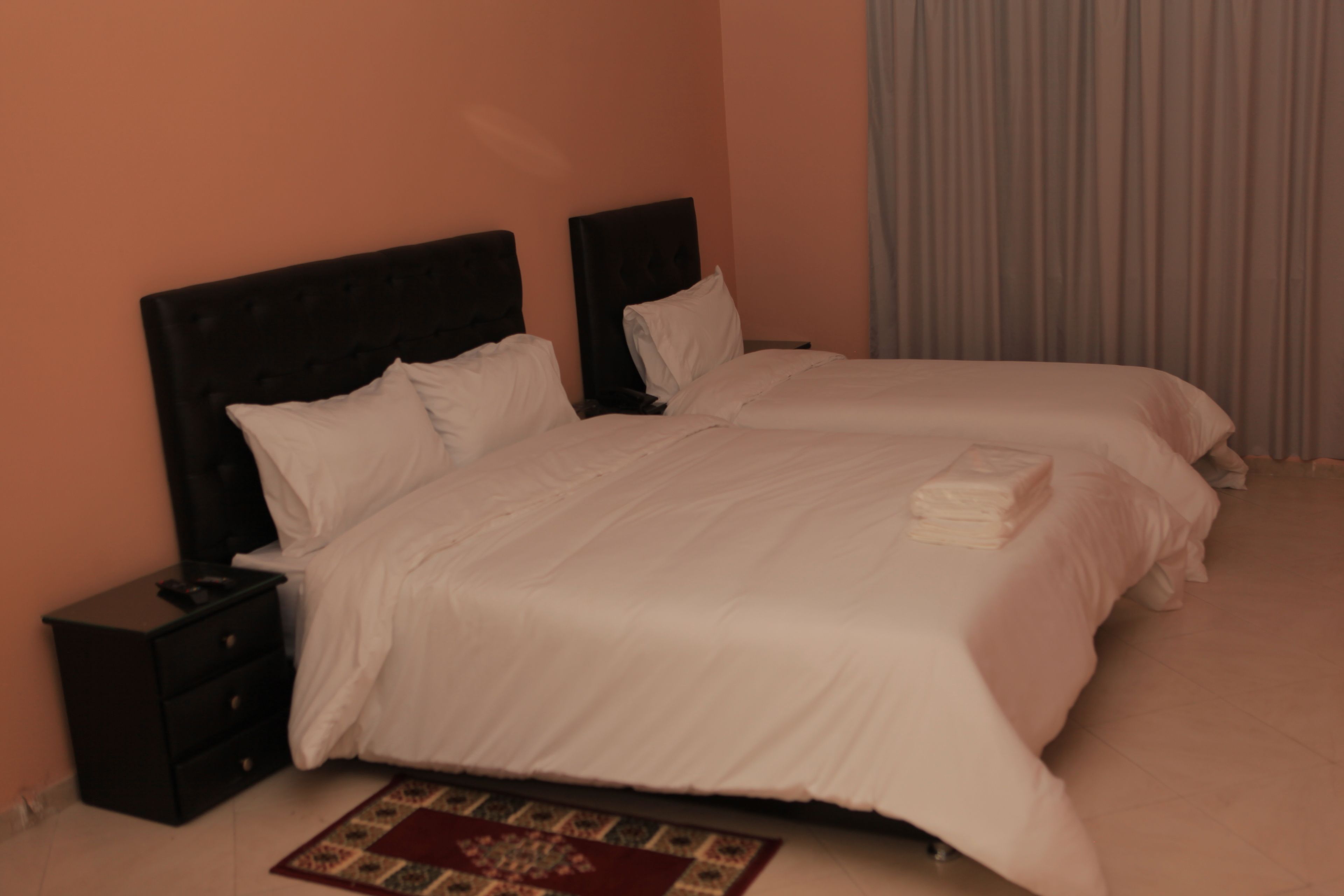 A double bed with a headboard, a nightstand, and a bedside table.
