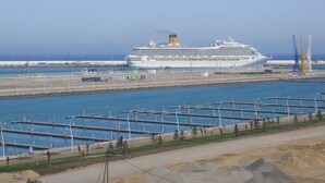 Un gran crucero amarrado en un puerto con un puerto deportivo al frente.