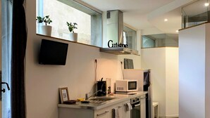 Una cocina moderna con armarios blancos, microondas integrado y una campana extractora de acero inoxidable.
