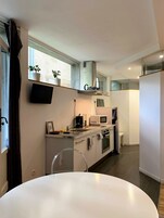 Cozinha moderna com armários brancos, micro-ondas embutido e coifa em aço inoxidável.