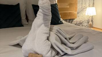 Ein ordentlich bezogenes Bett mit einem weißen Handtuch, einem Holzschild und einer Lampe auf einem Nachttisch.