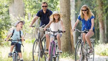 Une famille de quatre personnes fait du vélo dans une zone boisée.