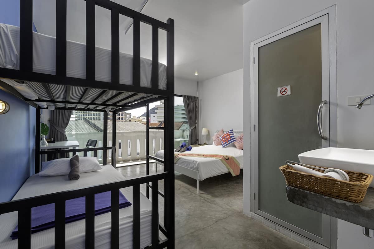 Una habitación con literas, una cama individual, baño con lavamanos y vistas a la ciudad.