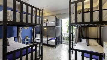 Un dormitorio con literas, una mesita con una planta y una ventana con cortinas.
