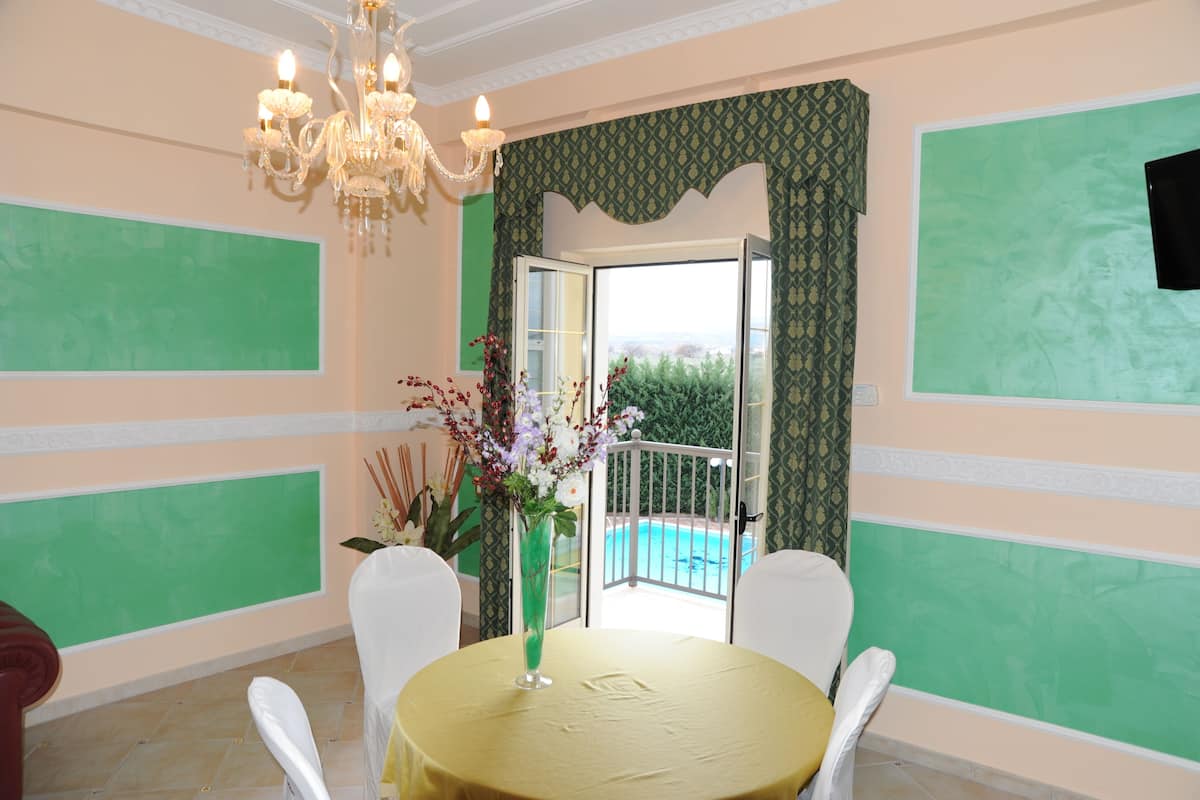 A dining area with a round table, chairs, a chandelier, and a view of a swimming pool.