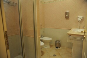 A bathroom with a glass shower enclosure, a toilet, a bidet, a sink, and a trash can. - Hotel Villa Santa Maria (Cerchiara di Calabria)
