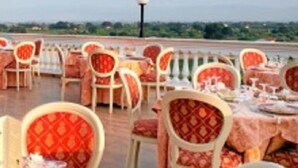 Un restaurant doté d’une terrasse, de chaises rembourrées de couleur rouge et offrant une vue sur le paysage.