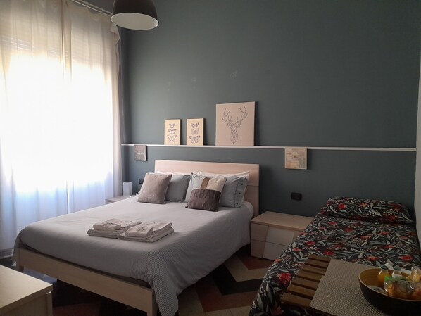 A neatly arranged bedroom with a bed, bedside tables, and a small table with a bowl of fruit. - Lavilletta B&B (Salerno)
