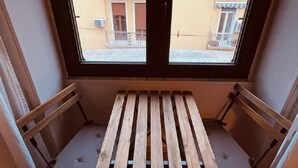 Un balcó amb taula de fusta i dues cadires, amb vista a un edifici amb balcons i finestres.