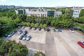 A parking lot with multiple cars and a large building in the background. - Ausotel Select Guangzhou Baiyun International Airport - Canton Fair courtesy shuttle bus from October 14 to November 4 (Guangzhou)