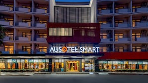 A hotel with multiple balconies, a prominent entrance, and a sign reading "AUSOTEL SMART".