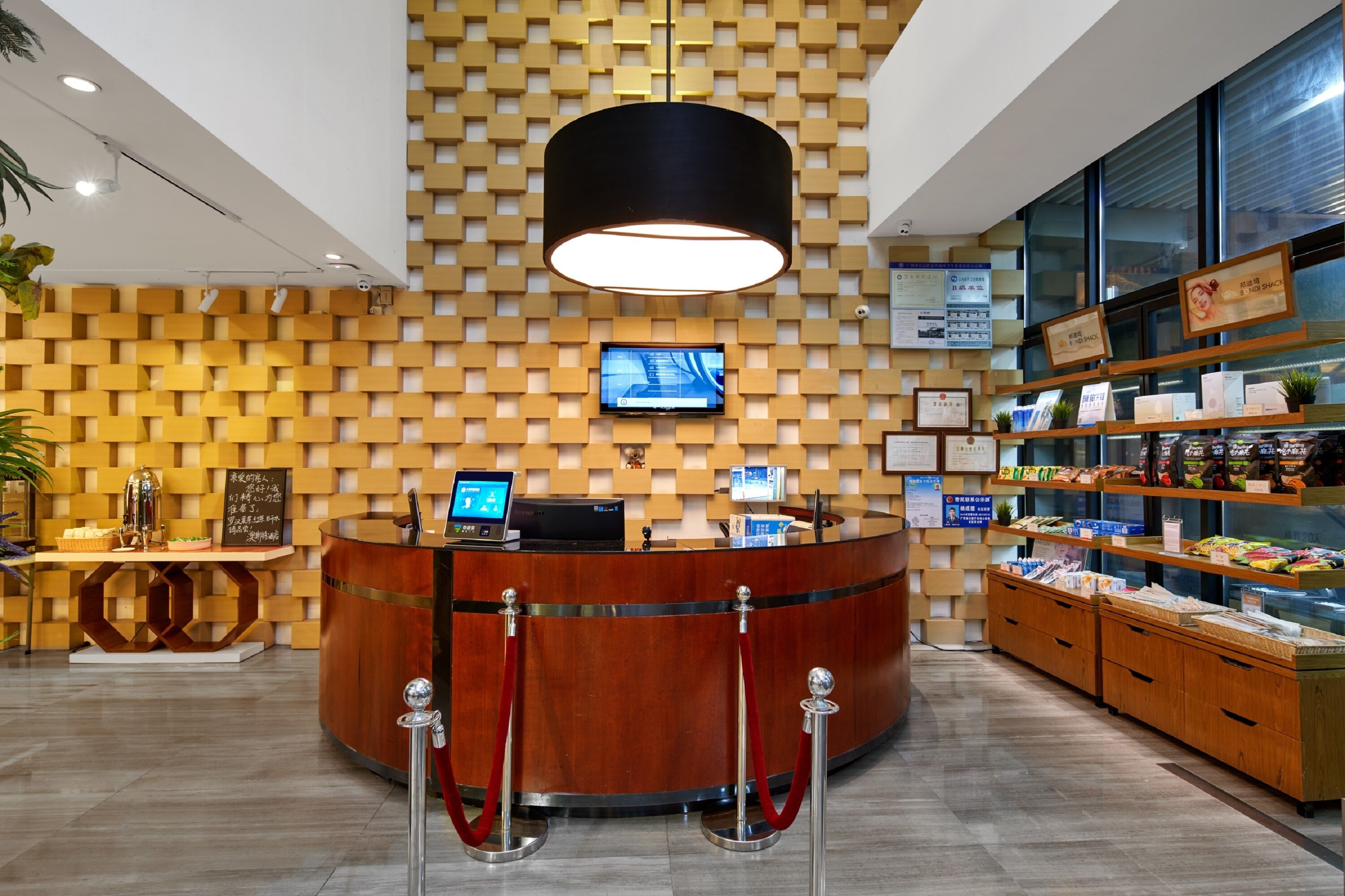 A reception area with a wooden reception desk, a digital screen, and a wall-mounted TV.