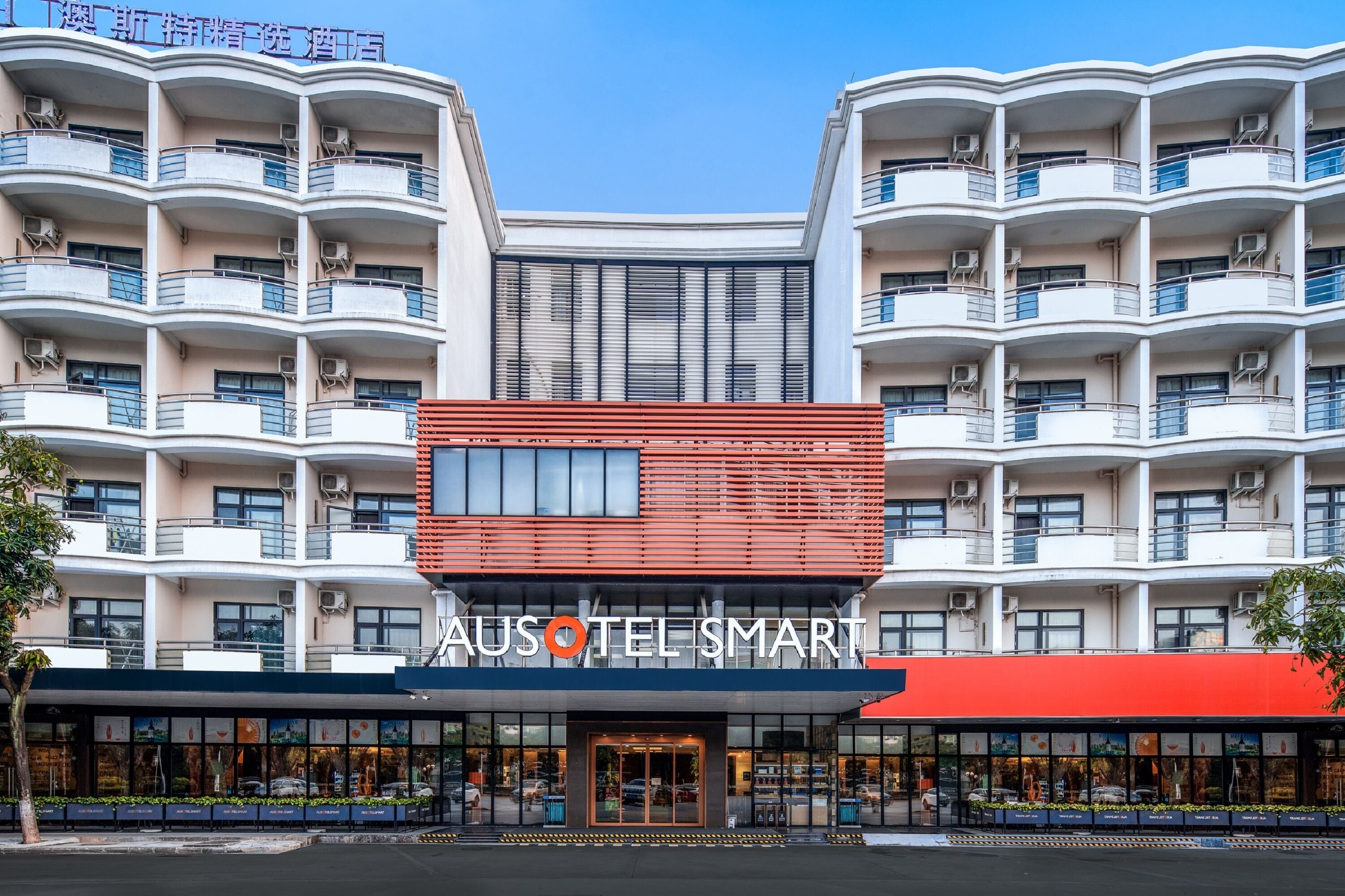 A multi-story hotel with a modern facade, balconies, and a prominent signage for "AUSOTEL SMART".