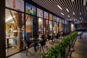 A modern hotel with a long corridor lined with tables and chairs, large windows, and a patterned ceiling. - Ausotel Select Guangzhou Baiyun International Airport - Canton Fair courtesy shuttle bus from October 14 to November 4 (Guangzhou)