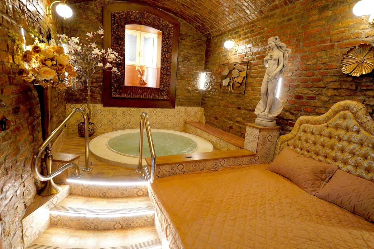 Een luxe badkamer met een bad, een beeld en een decoratieve spiegel.