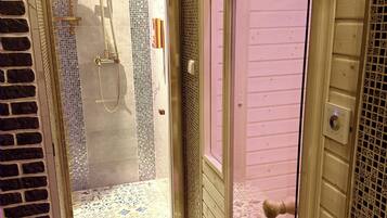 A bathroom with a shower, tiled walls, and a patterned floor.