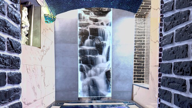 Un espace de bien-être doté d’une cascade, d’un jacuzzi et de murs en pierre.