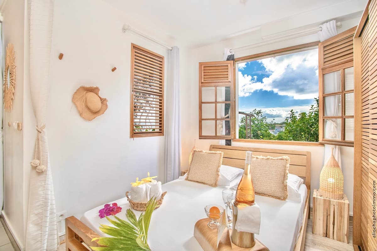 A neatly arranged bedroom with a bed, bedside table, and a window with a view of greenery.