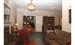 A cozy living room with a fireplace, multiple armchairs, a sofa, and a bookshelf. - The Pines Hotel (Slough)
