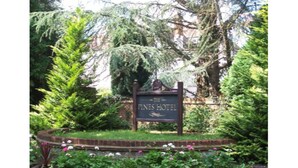 A sign for The Pines Hotel surrounded by lush greenery. - The Pines Hotel (Slough)