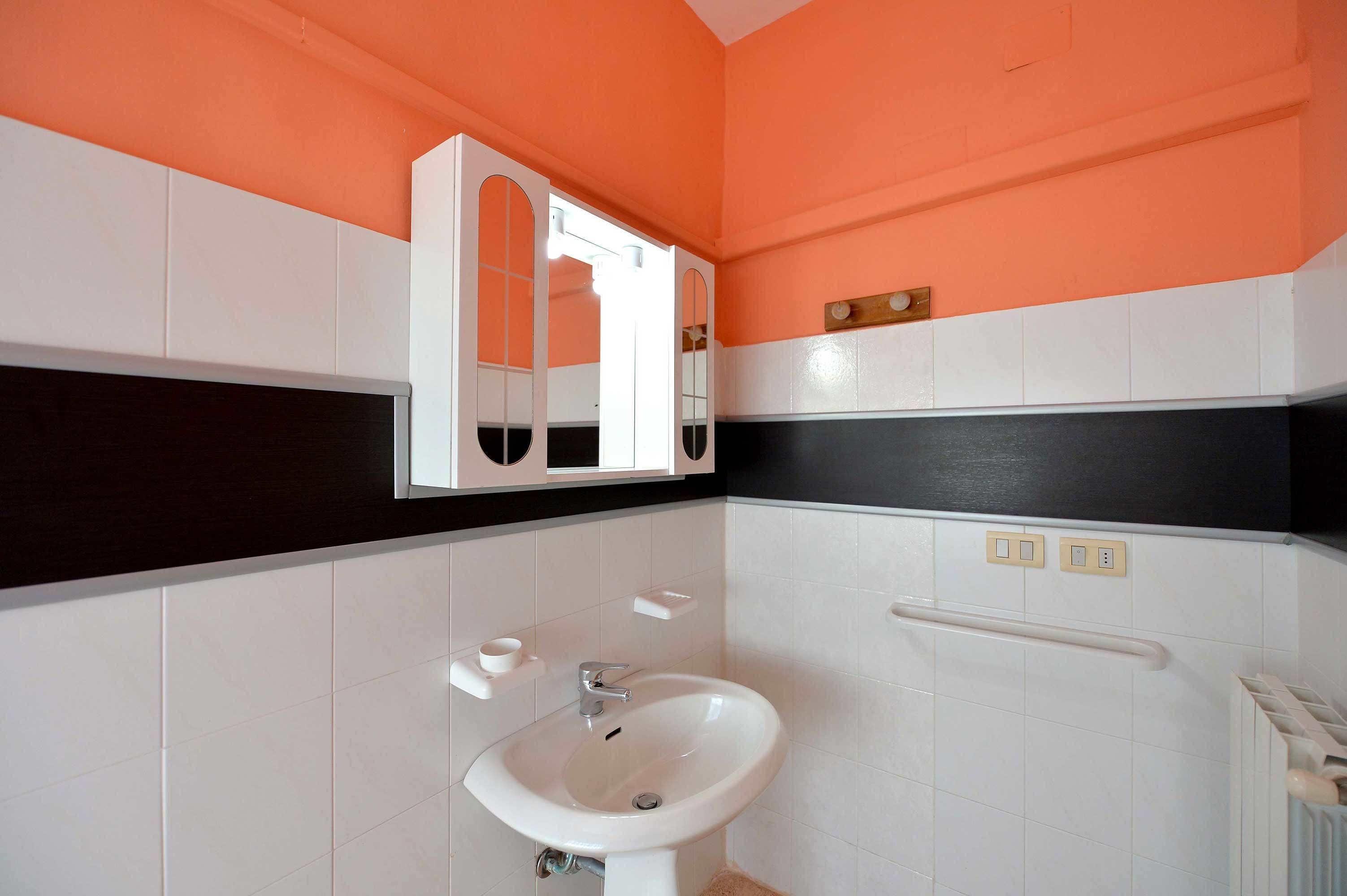 A bathroom with a white sink, a mirror, and a towel rack.