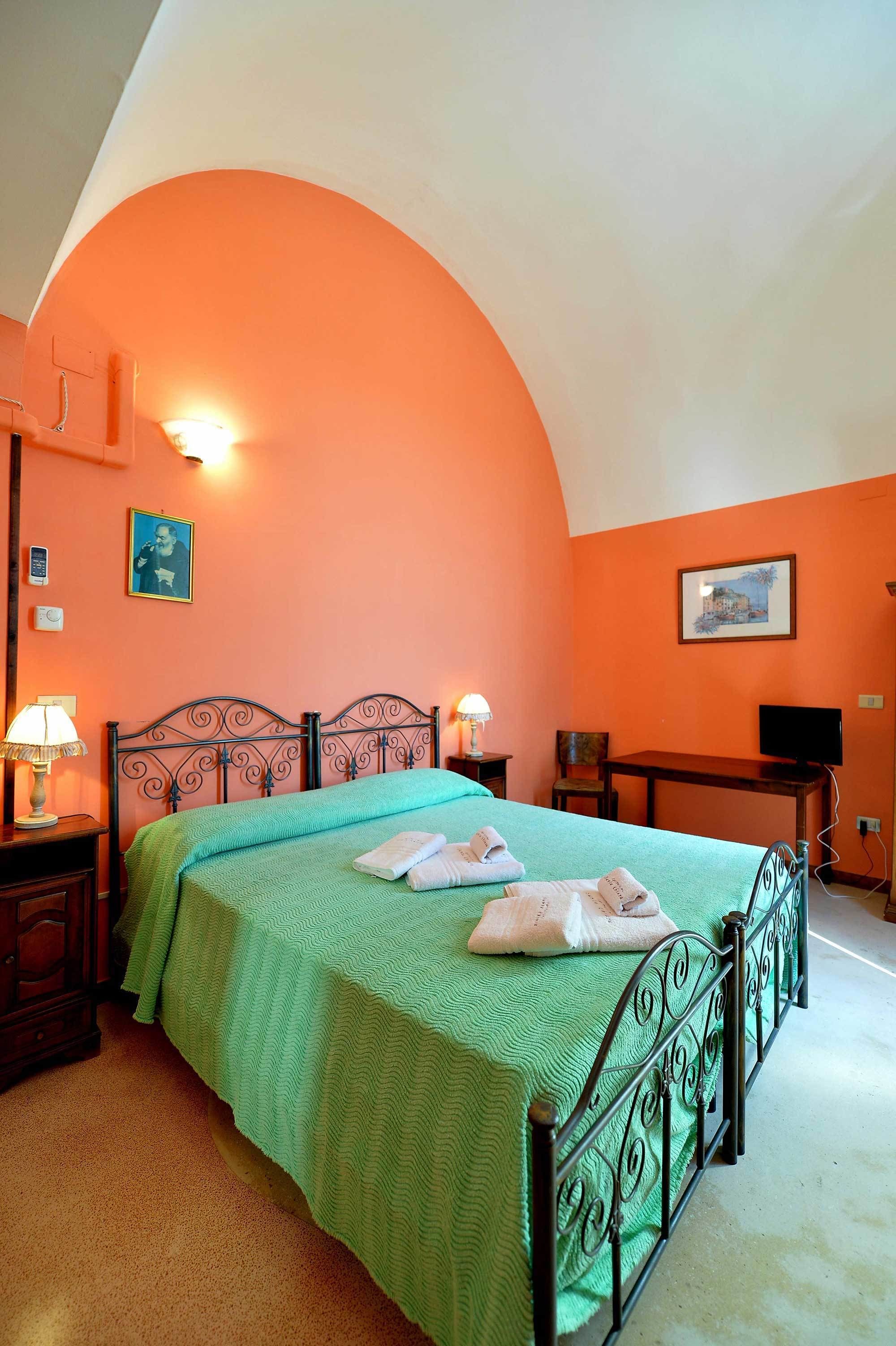 A room with a bed, two bedside tables, a desk, and a chair.
