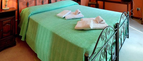 A room with a bed, two bedside tables, a desk, and a chair.