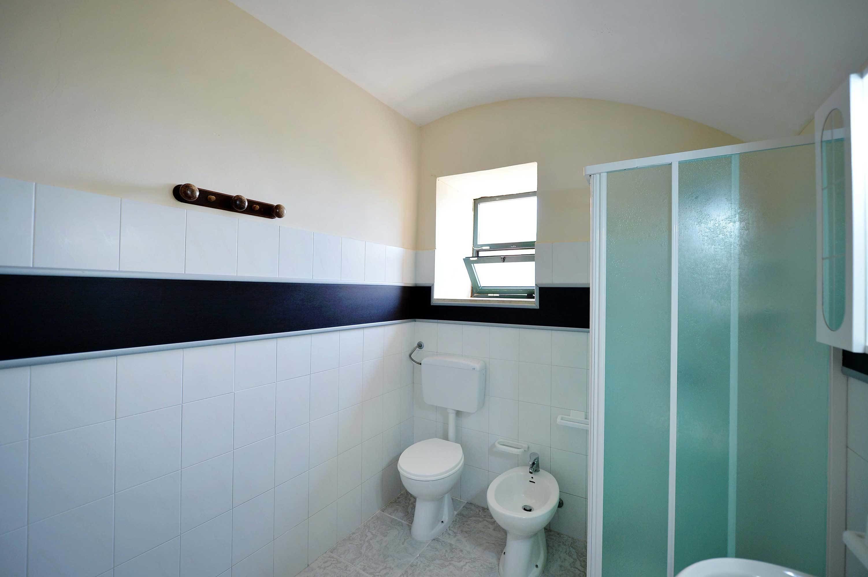 A bathroom with a toilet, bidet, and a glass-enclosed shower area.