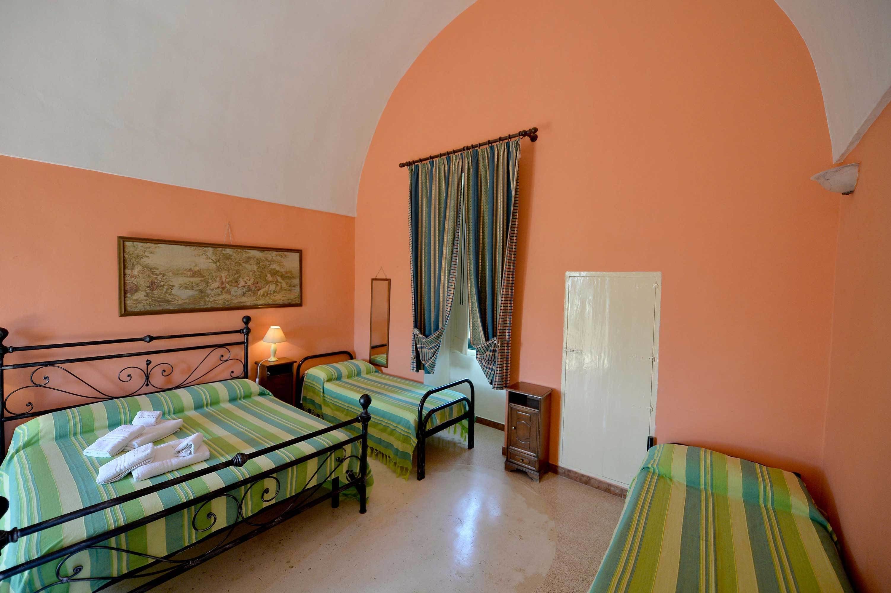 Une chambre avec deux lits, une petite table de chevet avec une lampe, une armoire et une porte.