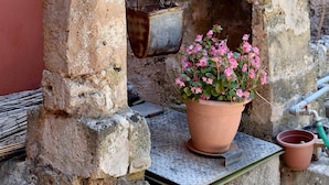 A rustic stone structure with terracotta pots containing red and pink flowers. - Agriturismo Santa Chiara (Alezio)
