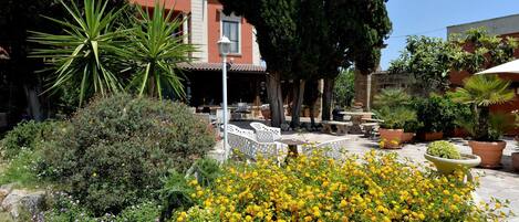 Un patio con zona de estar, plantas en macetas y un edificio de fachada roja.