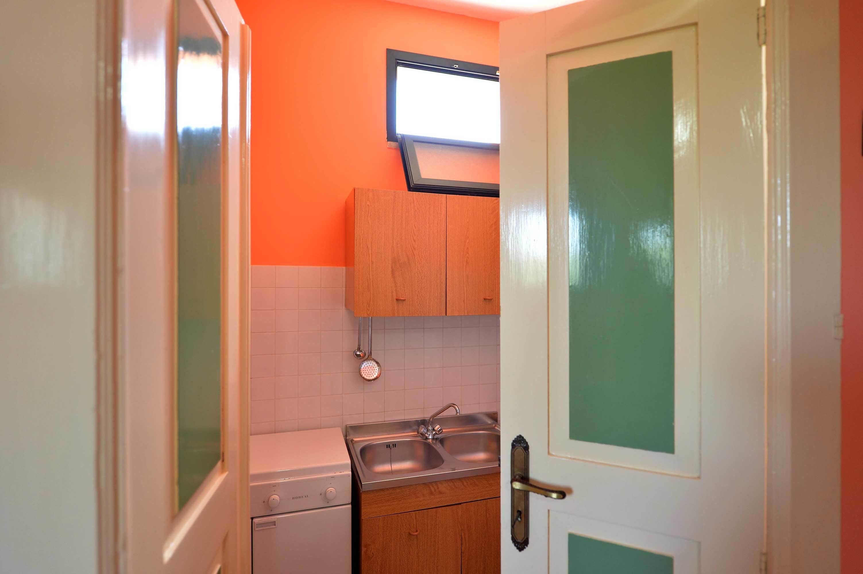 A compact kitchen with a washing machine, a sink, and wooden cabinets.