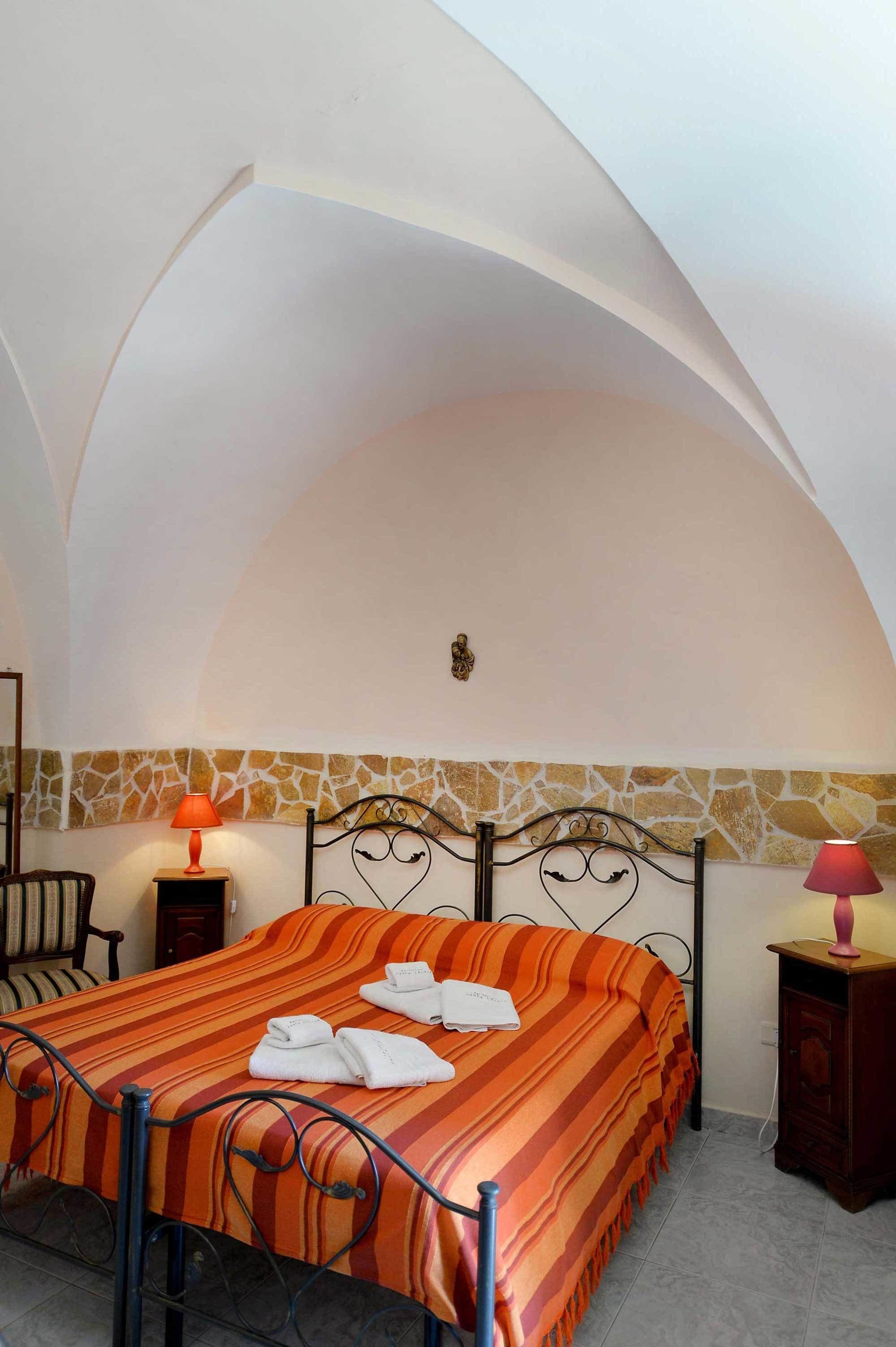 Un dormitorio con cama, una silla, una mesita de noche y una lámpara.