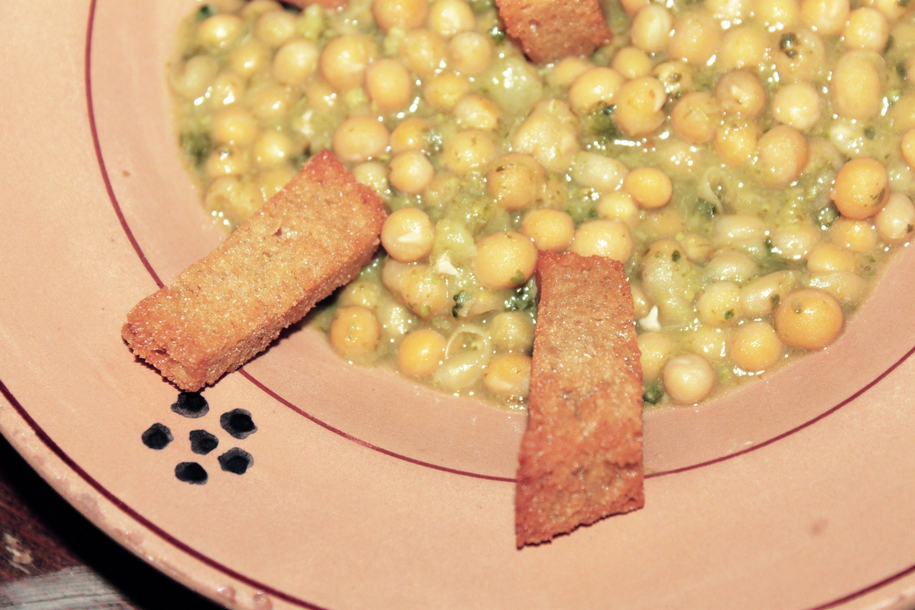 Un bol de soupe aux pois chiches et des gressins sur une assiette.