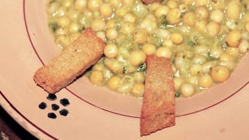 Un tazón de sopa con garbanzos y palitos de pan en un plato.