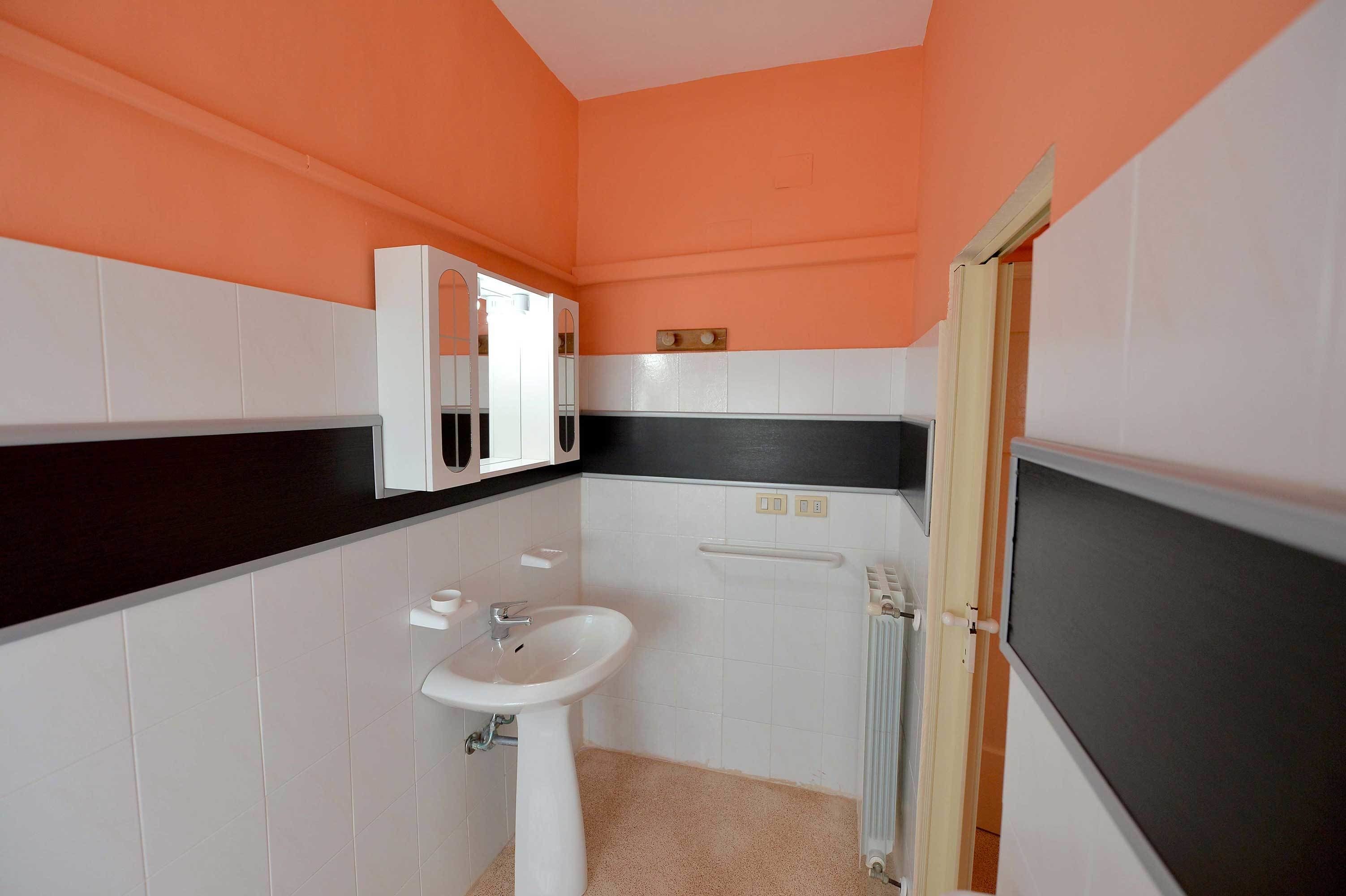 A bathroom with white and black tiled walls, a white sink, and a mirror.