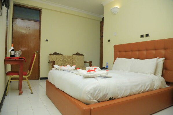 A hotel room with a bed, a desk, a chair, and a wardrobe.