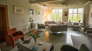 A spacious living room with multiple seating areas, a fireplace, and large windows providing natural light. - Hotel Laugar (Laugar)