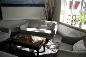 Una sala de estar con sofá, una mesa de centro y una ventana que ofrece vistas a la montaña y al mar.