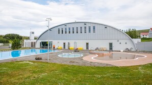 A modern building with a large pool area, including a circular hot tub and a rectangular swimming pool. - Hotel Laugar (Laugar)
