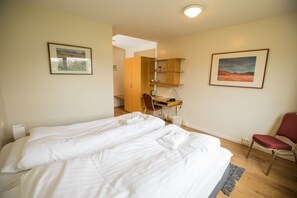 Een hotelkamer met twee bedden, een bureau, een stoel en een kleine kitchenette.