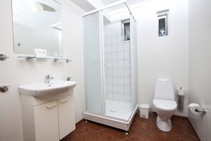 Un baño con ducha envuelta en cristal, un lavabo blanco y un inodoro.