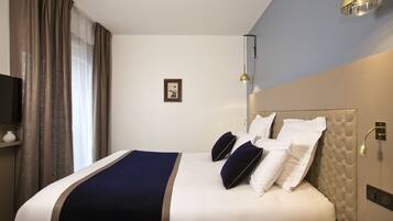 A neatly made bed with a blue and white bedspread, a headboard with a tufted design, and a bedside table with a lamp.