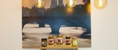 A display of bread and jams with a cityscape painting in the background.